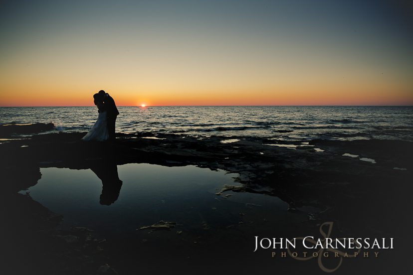 Bride and groom holding hands by the water at Bayshore Grove in Oswego NY