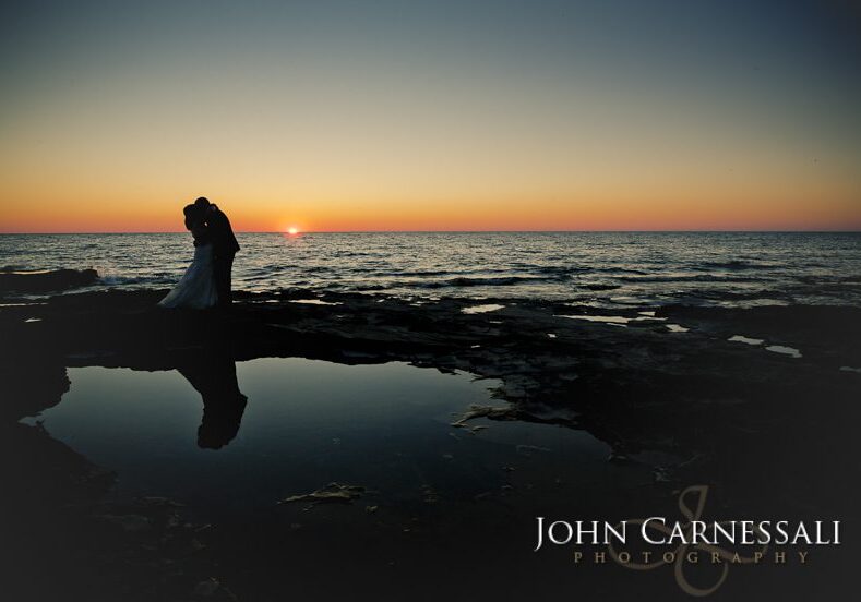 Bride and groom holding hands by the water at Bayshore Grove in Oswego NY