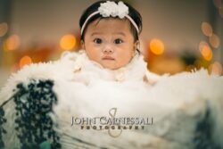 Studio newborn photography shot of a baby in a basket with twinkling lights behind