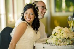 Bride and groom laughing at reception table.