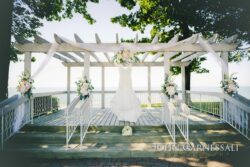Wedding gown hanging under lakeside pergola