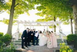 Wedding party celebrating under outdoor pergola.