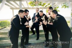 Groomsmen jokingly reacting to groom's hand gesture.
