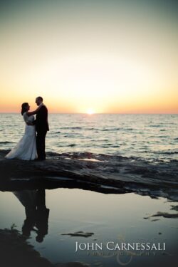 Bride and groom standing together by the water at Bayshore Grove in Oswego NY