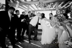 Bridal party tugging couple into kiss