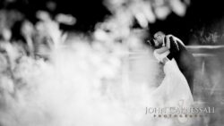 Bride and groom embrace in natural setting.