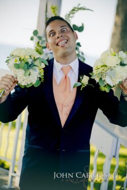 Man in suit playfully holding flower bouquets.
