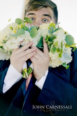 Person playfully hiding behind flower bouquet.