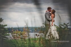 Couple kissing on grassy lakeside overlook