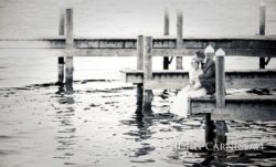 Bride and groom sitting on a pier.