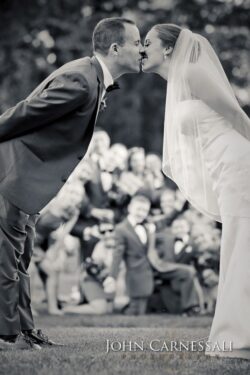 Bride and groom kissing, outdoor wedding ceremony.