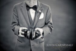 Boy in suit holding a camera.