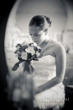 Bride holding bouquet, looking down, in mirror.