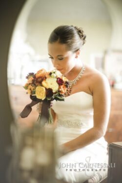 Bride holding bouquet, looking down, indoors.