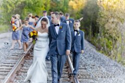 Bride, groom, and party on railroad tracks.