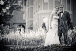 Bride and groom smiling in garden setting.
