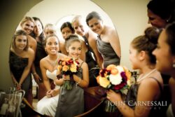 Bridesmaids and bride smiling in mirror reflection.