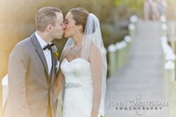 Bride and groom kissing on lakeside dock