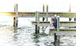 Bride and groom on lakeside dock at sunset