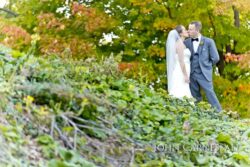 Wedding couple sitting by the water at Belhurst Castle in Geneva NY, Seneca Lake wedding day portraits