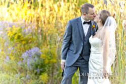 Groom in gray tux kisses veiled bride