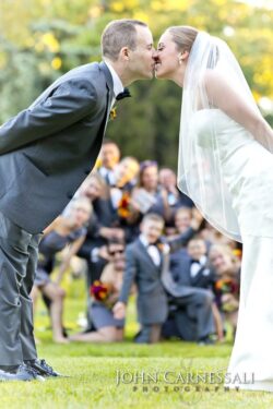 Couple leaning in to kiss with guests behind