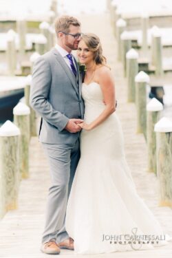 Wedding couple embracing at the waterfront railing at Belhurst Castle in Geneva NY, Finger Lakes wedding photography