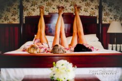 Three people lying on bed, legs raised.