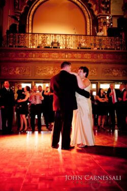 Couple dancing at elegant event, warm lighting.