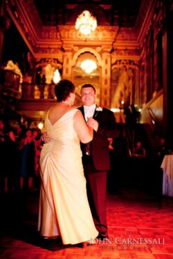 Couple dancing in elegant, warmly lit ballroom.