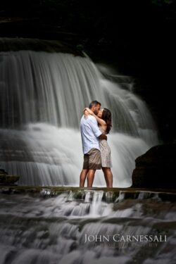Upstate NY waterfall engagement photo of couple kissing in front of cascading falls