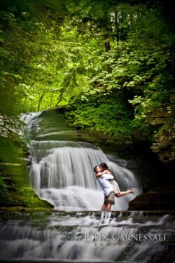 Ithaca NY Waterfall engagement photo of couple kissing beside a small waterfall