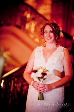 Bride holding bouquet on ornate staircase.