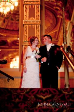 Bride and groom smiling on ornate staircase.