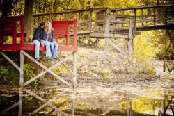 engagement photo of couple sitting on rustic wooden structure, fall engagement session countryside