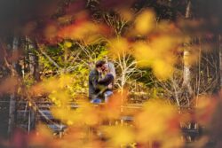 engagement proposal photo of man kneeling to propose framed by fall leaves, candid engagement photography