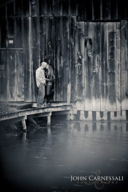 engagement photo in black and white of couple on boardwalk with water reflections, artistic couples portrait