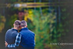 LGBTQ engagement photo of two men sitting together from behind, natural candid couple portrait