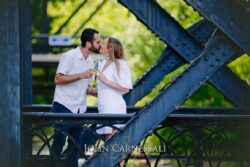 Franklin Square Syracuse NY engagement photo of couple kissing on a blue steel bridge, downtown Syracuse engagement photographer
