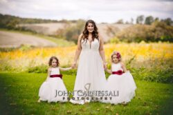 Bride with two flower girls in field.