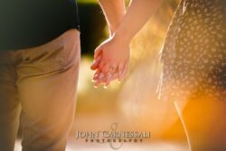 engagement photo of couple holding hands close-up with warm sunset backlight, engagement detail portrait