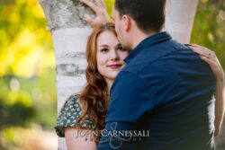 engagement photo of woman looking at camera with partner in foreground, candid couples portrait