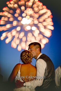 Syracuse Wedding Photography Text: Bride and groom kissing beneath fireworks