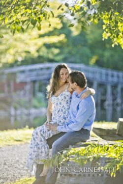 engagement photo of couple sitting together near a park bridge, natural candid couples portrait