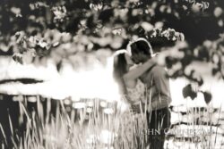 black and white engagement photo of couple hugging in a field, romantic documentary portrait
