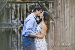 engagement photo of couple kissing near rustic wooden wall, romantic natural light portrait