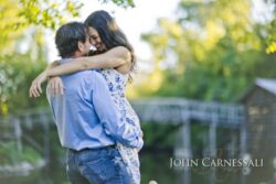 engagement photo of couple hugging near a park bridge, romantic candid engagement portrait