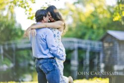 engagement photo of couple embracing near a park bridge, natural candid couples portrait