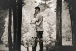 black and white engagement photo of couple standing close together outdoors, romantic couples portrait