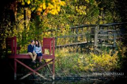 engagement photo of couple sitting together in a rustic fall setting, warm autumn engagement portrait